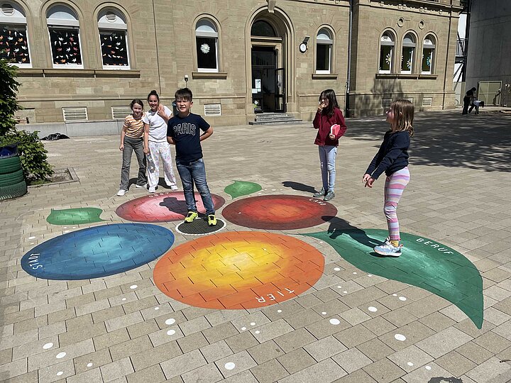 Kinder spielen Stadt-Land-Obst mit Hilfe der Blume auf dem Schulhof