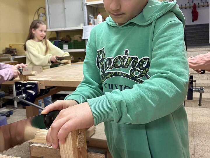 Kind beim Sägen von Holz