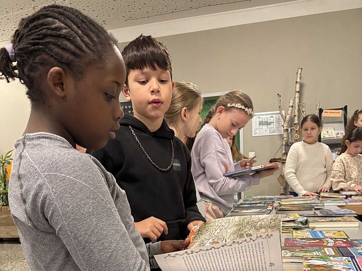 Schülerinnen und Schüler stöbern in der Buchaustellung