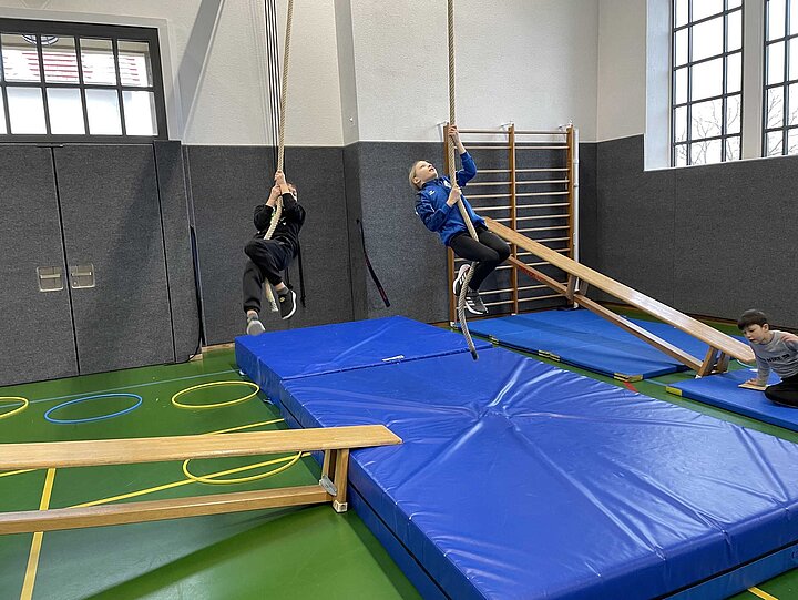 Eine Schülerin und ein Schüler beim Klettern am Seil