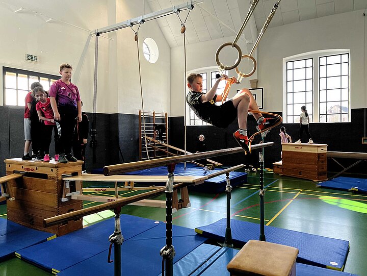 Schüler an den Ringen der Turnhalle im Rot