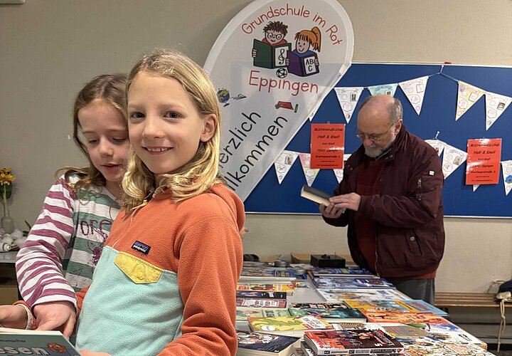 Schülerinnen schauen ein Buch bei der Buchausstellung von Herr Knoll an