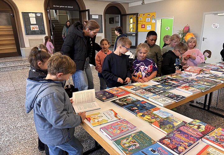 Schülerinnen und Scüler mit ihrer Lehrkraft am Bücherstand der Buchhandlung Holl & Knoll in der Aula