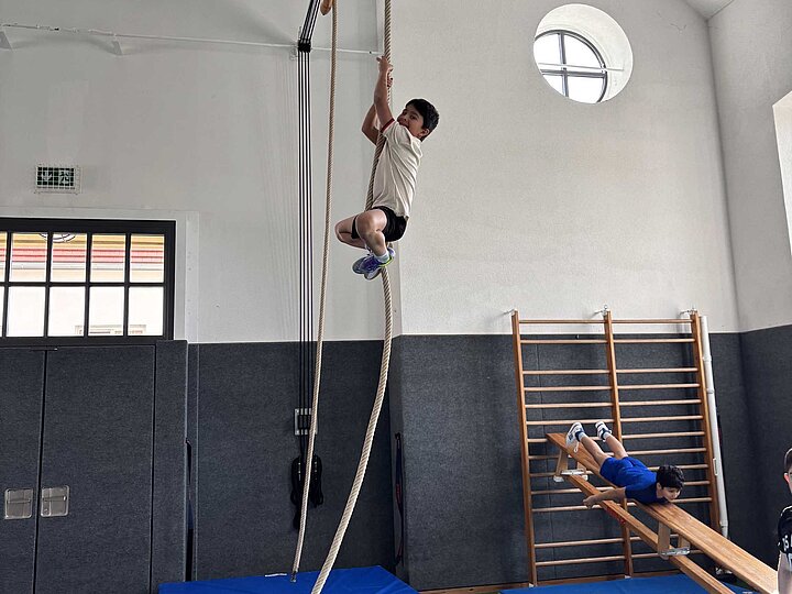 Schüler klettert am Seil hoch