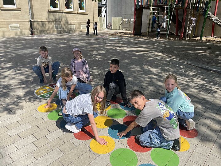Kinder beim Spiel "Twister" auf dem Schulhof